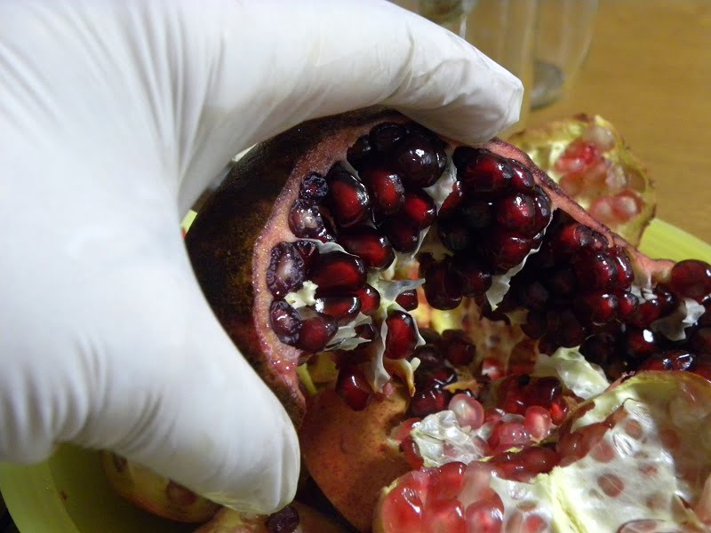 Peeling pomegranate wearing latex gloves image